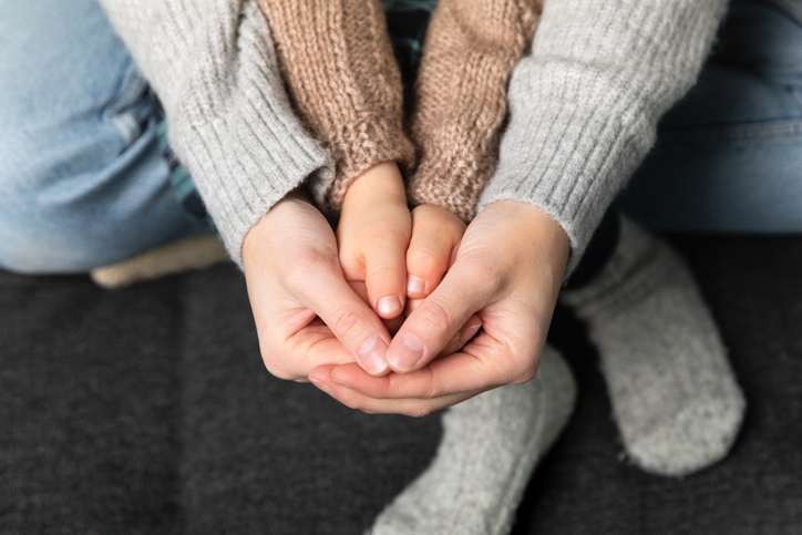 Women holding sons hand, knitted jumper and socks in background. Warming home and family concept.